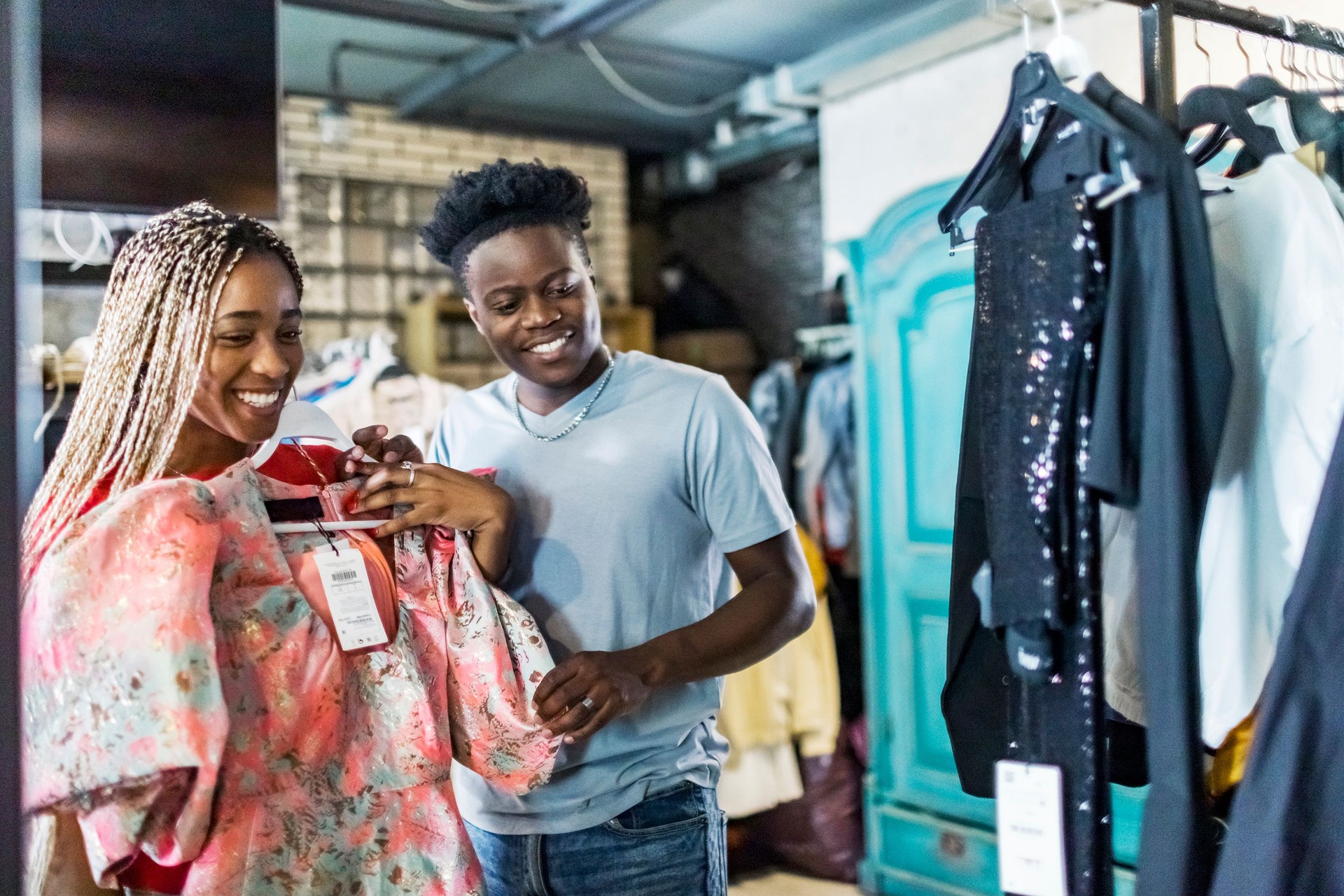 Young adult African couple choosing dress in second hand sale
